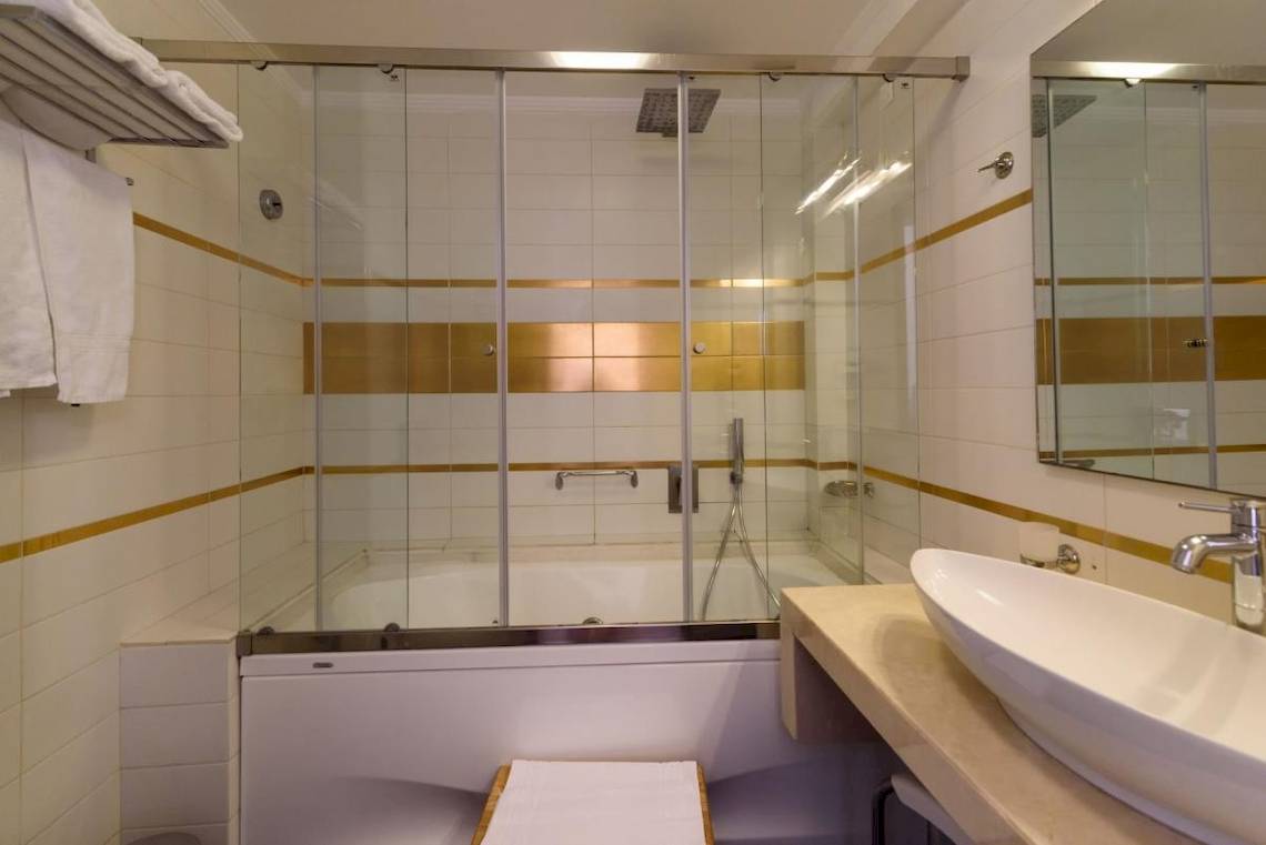 Badezimmer im La Mer Deluxe Hotel & Spa mit Glasdusche, Badewanne und Waschbecken.