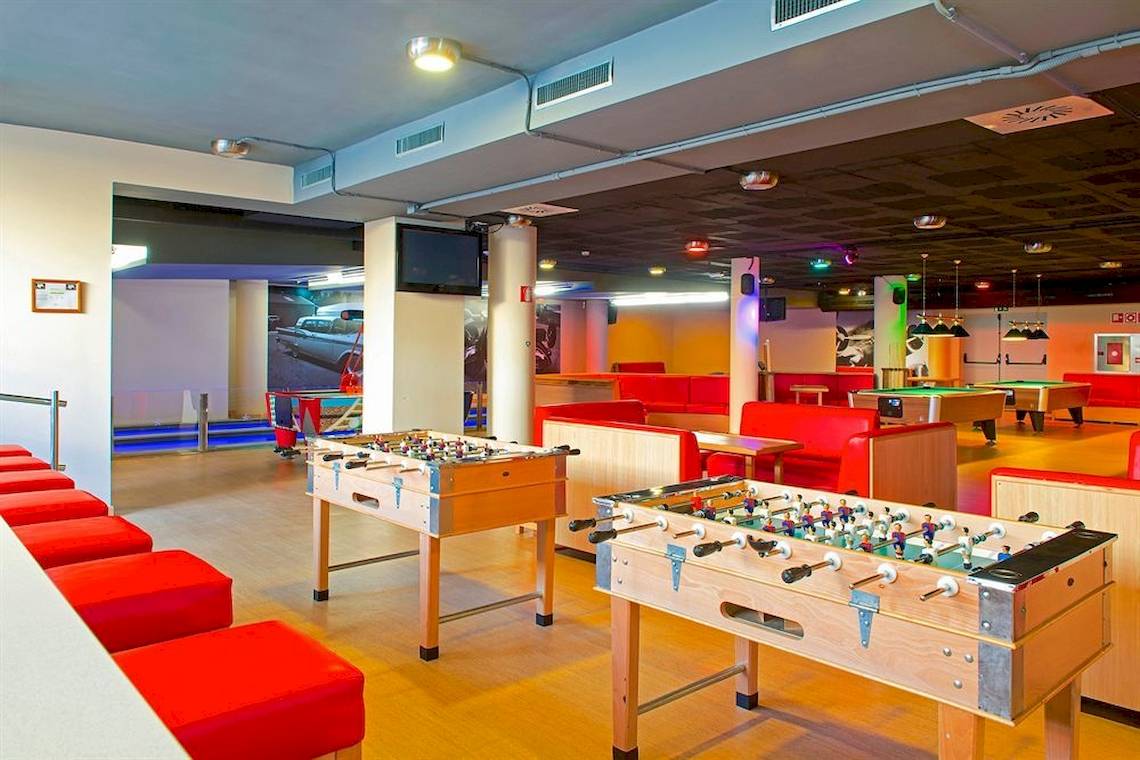 Hotellobby mit Spielbereich, inklusive Fußballtischen und Pooltischen, alles in rot und weiß.