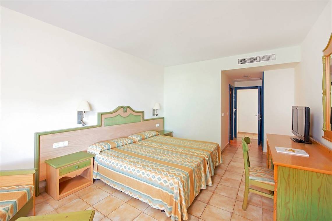Innenansicht eines Hotelzimmers im Iberostar Playa Gaviotas mit Doppelbett, Schreibtisch und Fernseher.