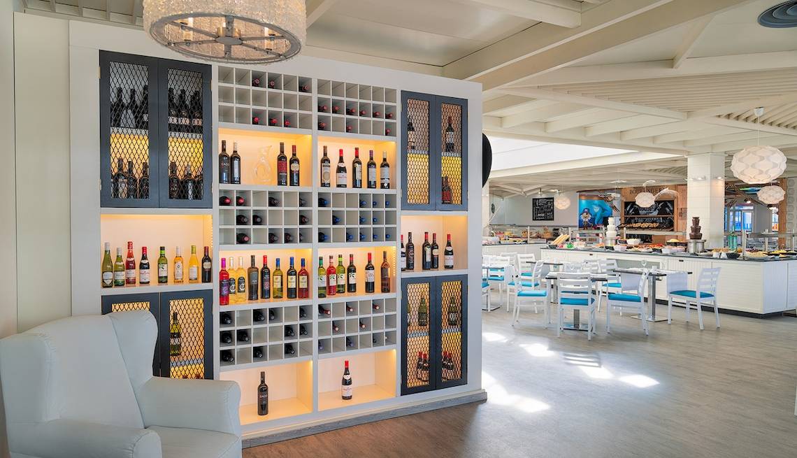 Restaurant im H10 Suites Lanzarote Gardens mit Weinregal und Tischen.