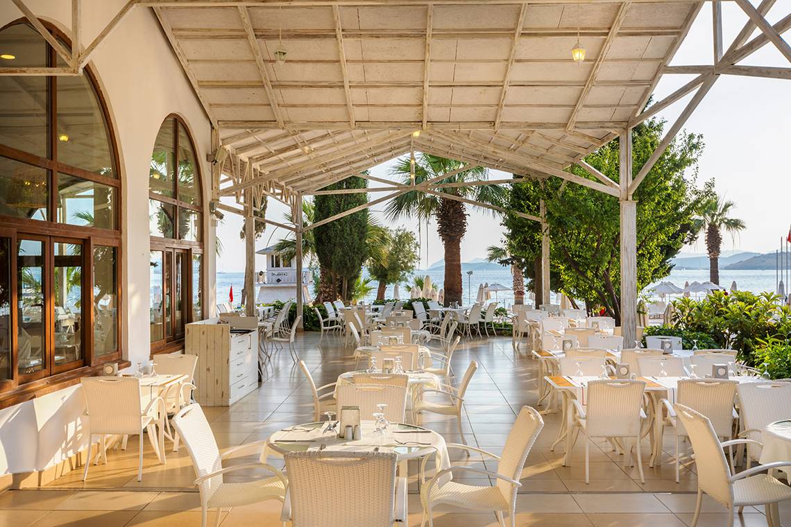 Terrasse im Freien des Labranda TMT Bodrum Hotels mit weißen Tischen und Stühlen.