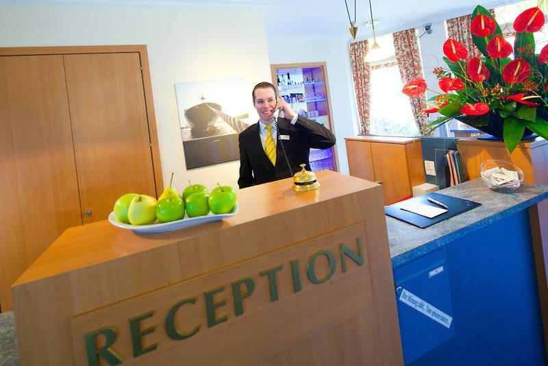 Reception Mitarbeiter im Hotel Hamburg Mitte telefoniert lächelnd