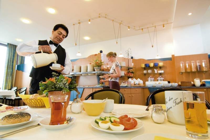 Ein Frühstückstisch im Hotel Hamburg Mitte mit Getränken, Brot, Gemüse und Eiern.