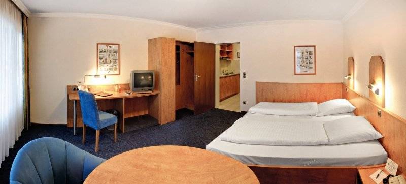 Hotelzimmer im Hamburg Mitte mit Schreibtisch, Fernseher, Betten und Stühlen.