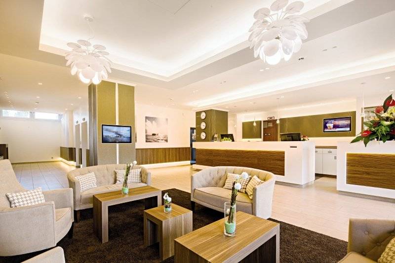 Empfangsbereich des Hamburg Mitte Hotels mit Sofas, Tischen und Fernsehern.