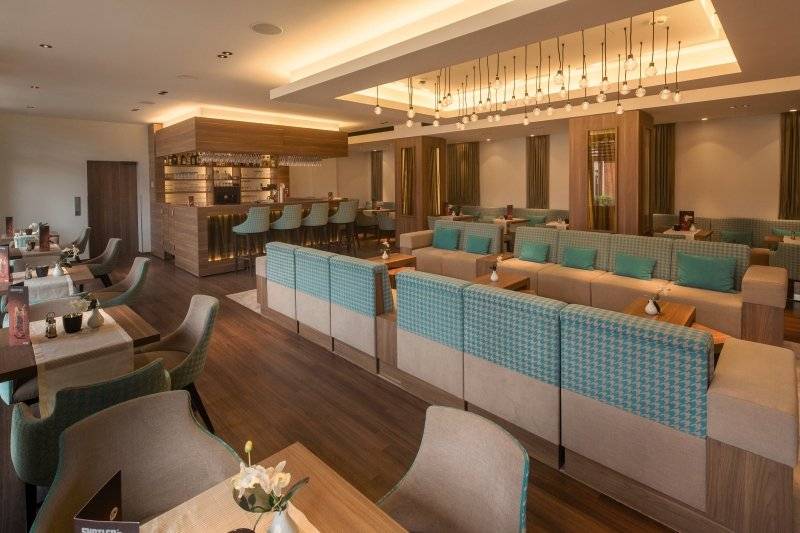 Innenbereich des Hamburg Mitte Hotels mit Bar, Sitzbereichen und Esstischen.