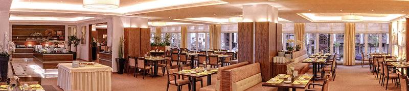 Restaurant im Hamburg Mitte Hotel mit vielen Tischen und Stühlen, dekoriert mit Pflanzen und Lampen.