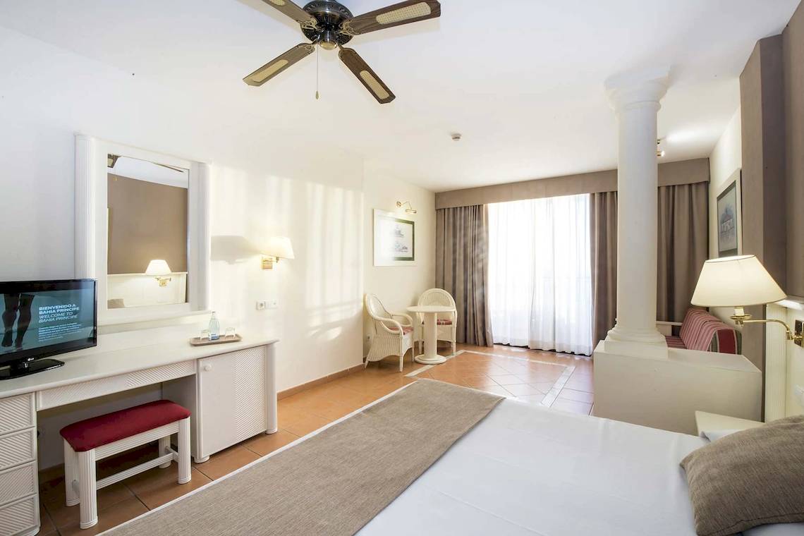 Innenansicht eines Hotelzimmers im Bahia Principe Sunlight Costa Adeje, mit Bett, Schreibtisch, Fernseher und Möbeln.