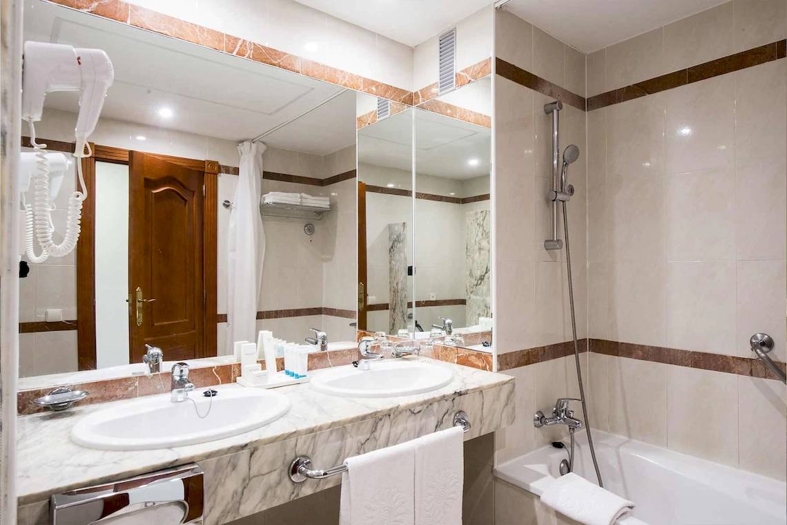 Ein Badezimmer mit zwei Waschbecken und einer Badewanne im Bahia Principe Sunlight Costa Adeje Hotel.