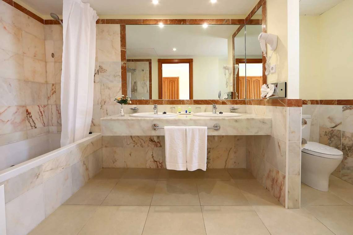 Ein Badezimmer im Bahia Principe Sunlight Costa Adeje Hotel mit Badewanne, Spiegel und Waschbecken.