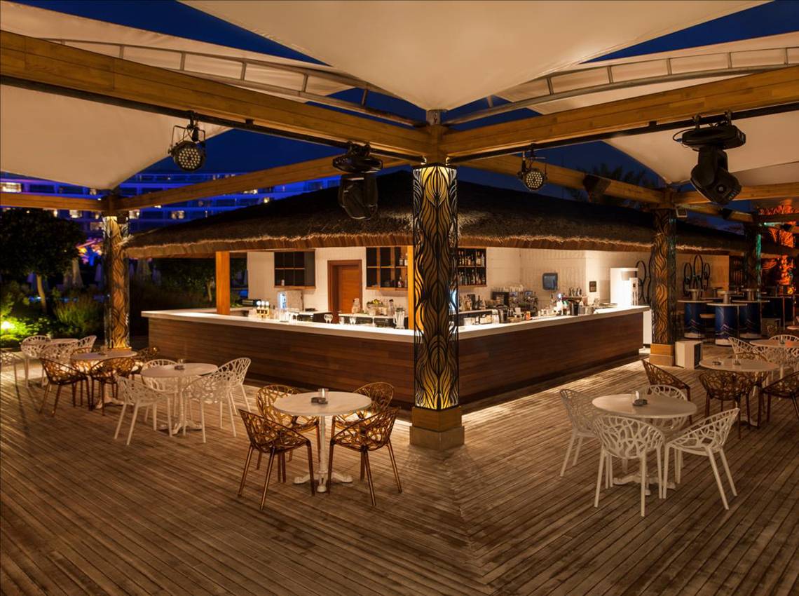 Außenbar des Maxx Royal Belek Golf Resort mit abendlicher Atmosphäre und Holzdekoration.