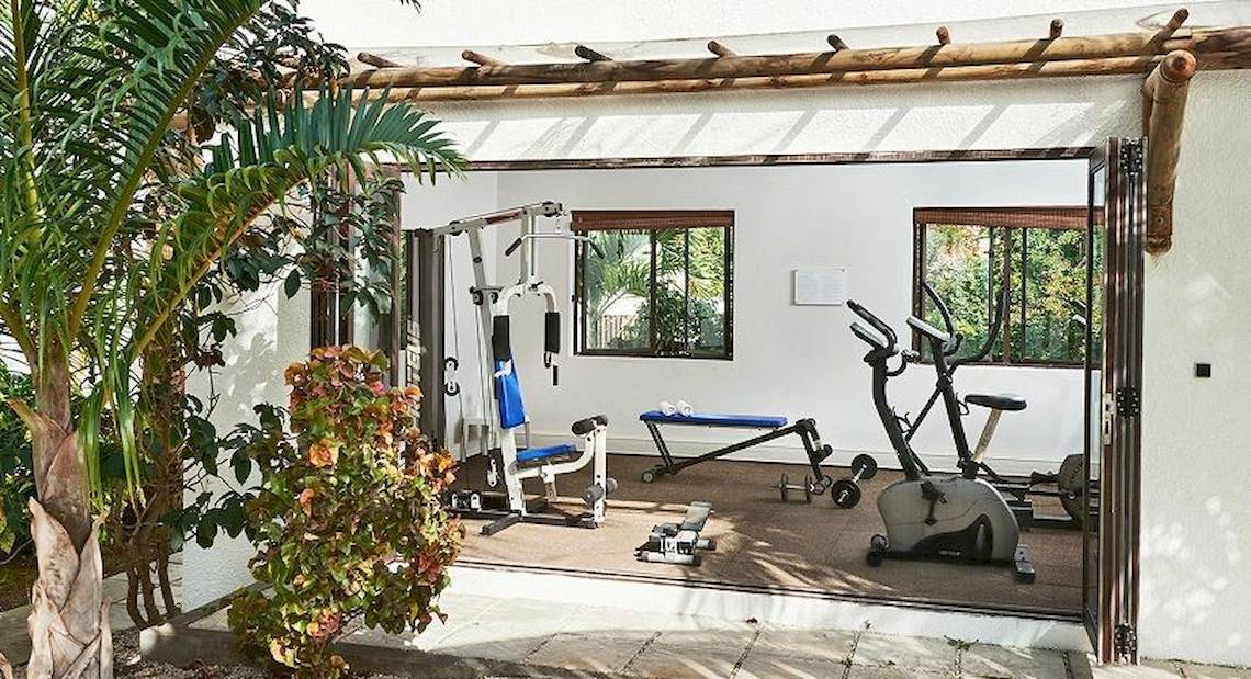 Fitnessraum im Recif Attitude Hotel mit Trainingsgeräten und einer offenen Tür.