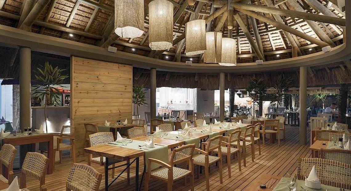 Innenansicht des Restaurants Recif Attitude mit Holztischen, Stühlen und Holzdecke.
