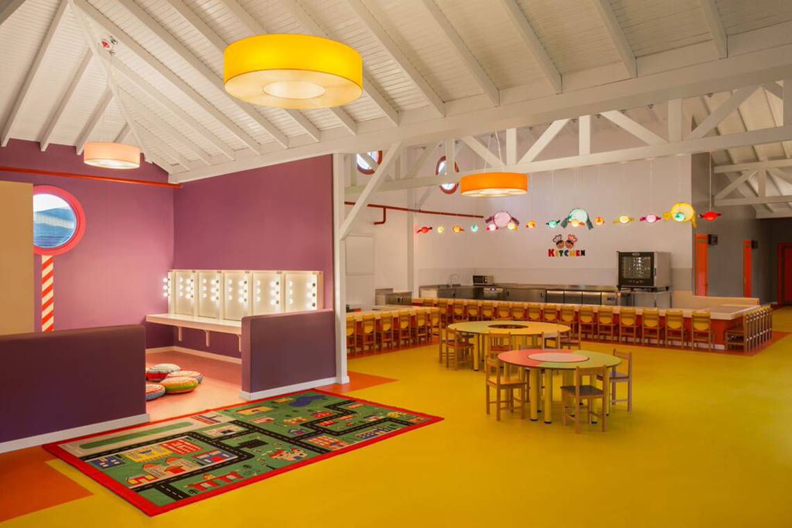 Kinderzimmer im IC Santai Family Resort mit bunten Farben, Tischen, Stühlen und Spielzeug.