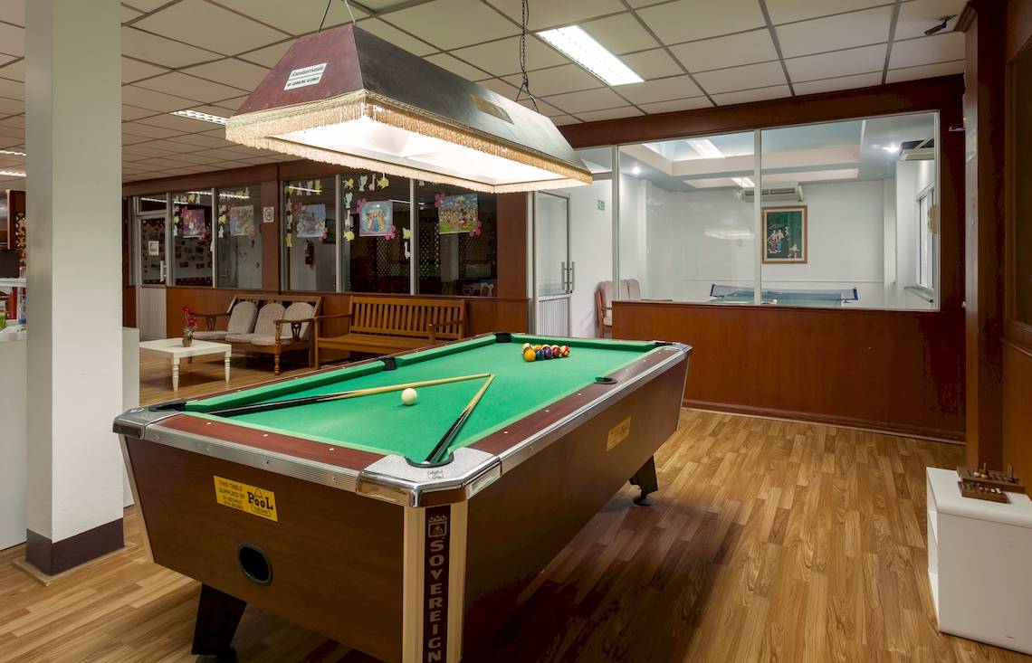 Ein Pooltisch im Innenbereich eines Hotels, mit Billardkugeln und Stöcken auf dem grünen Tisch.