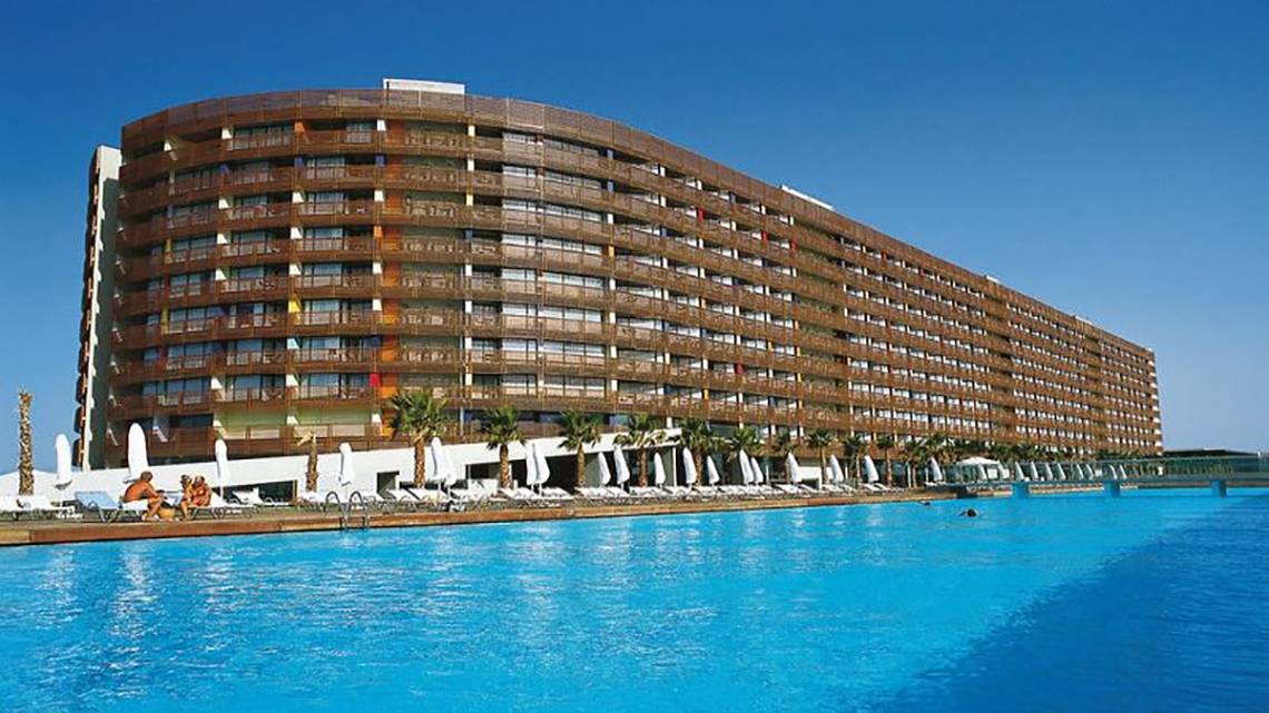 Außenansicht des Nirvana Cosmopolitan Hotels mit großem Swimmingpool und Sonnenliegen.