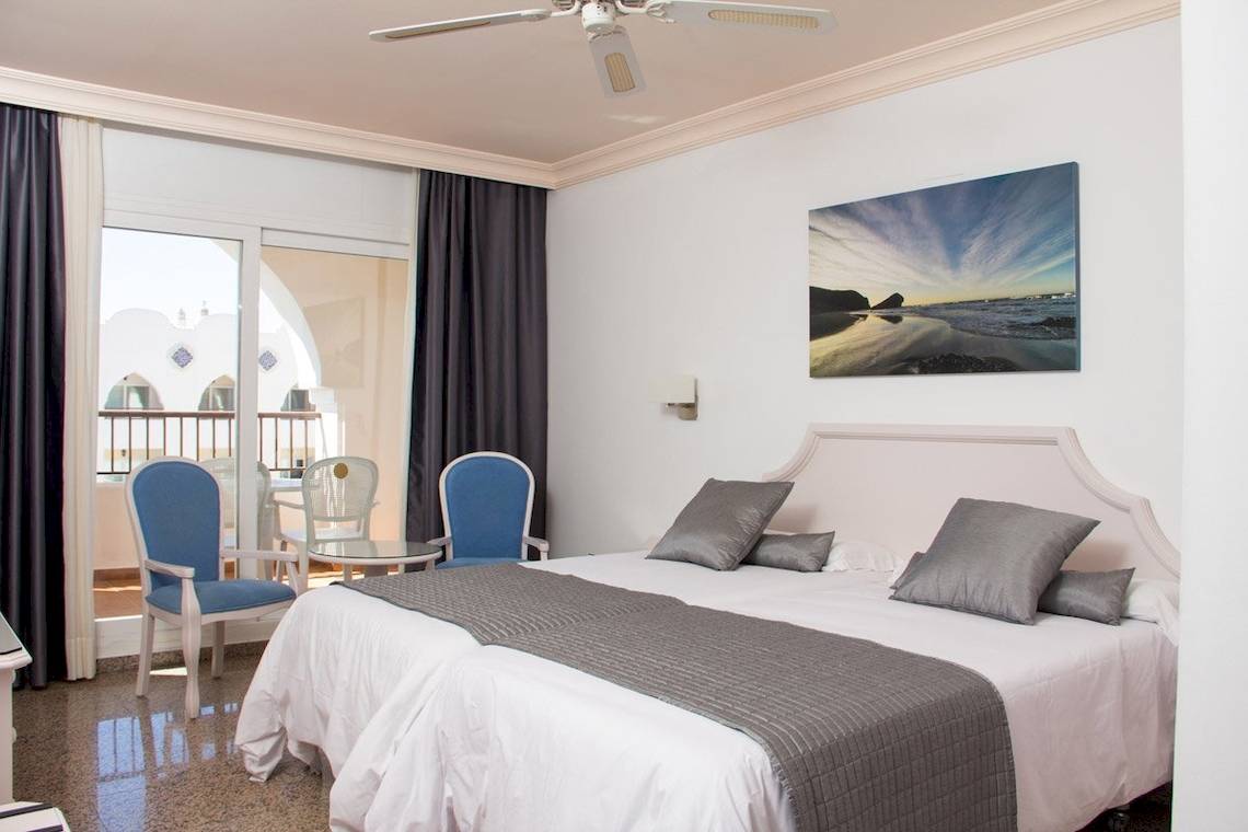 Schlafzimmer im MAC Puerto Marina Hotel mit zwei Betten, grauen Kissen und weißem Decken.