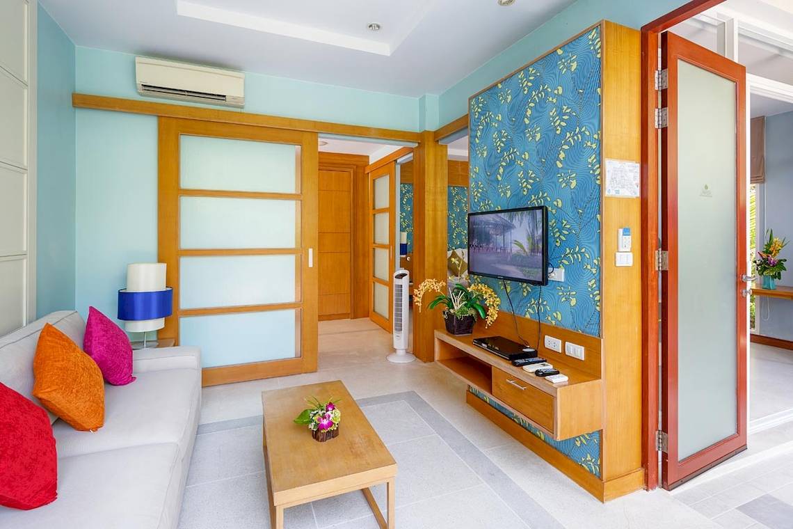 Wohnzimmer im Apsara Beachfront Resort und Villa mit blauen Wänden, Fernseher und Sofa.