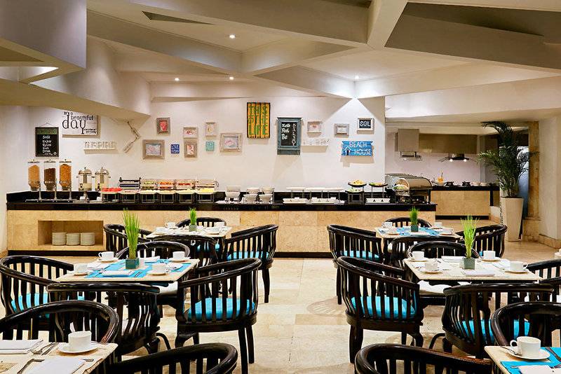 Innenansicht des Restaurants im Sol Benoa Bali Hotel mit Tisch, Stühlen und Buffet.