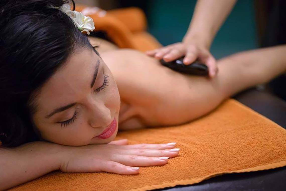 Frau im Royal Blue Resort erhält eine Massage mit einem schwarzen Stein.