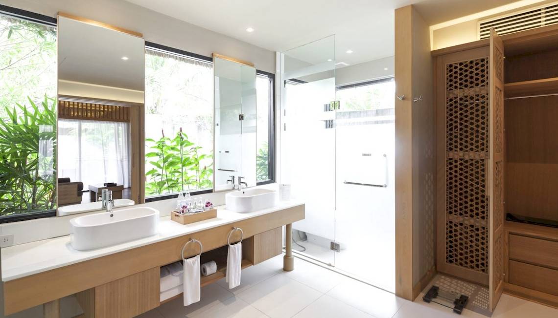 Badezimmer des Beyond Resort Khao Lak mit zwei Waschbecken und einer Dusche.