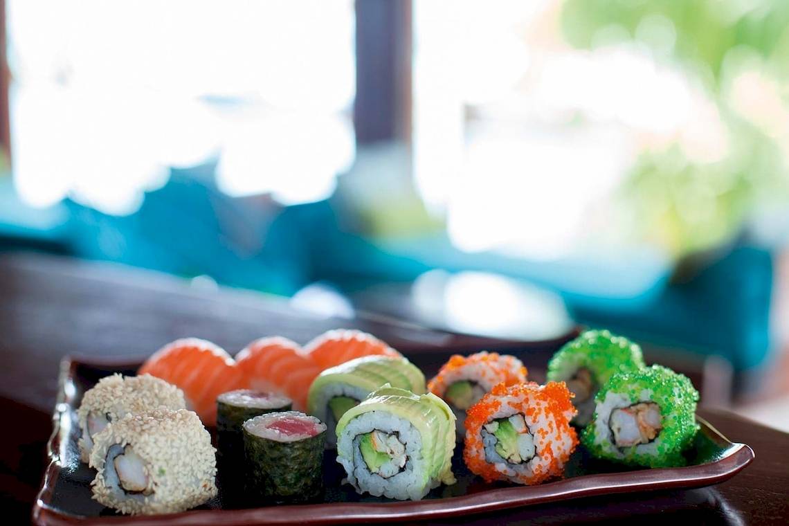 Verschiedene Sushisorten auf einem Teller in einem Restaurant.
