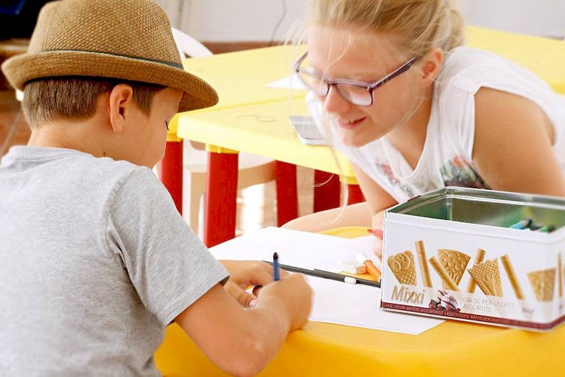Ein Kind mit Stift am Tisch im Hotel Colonna Country & Sporting Club