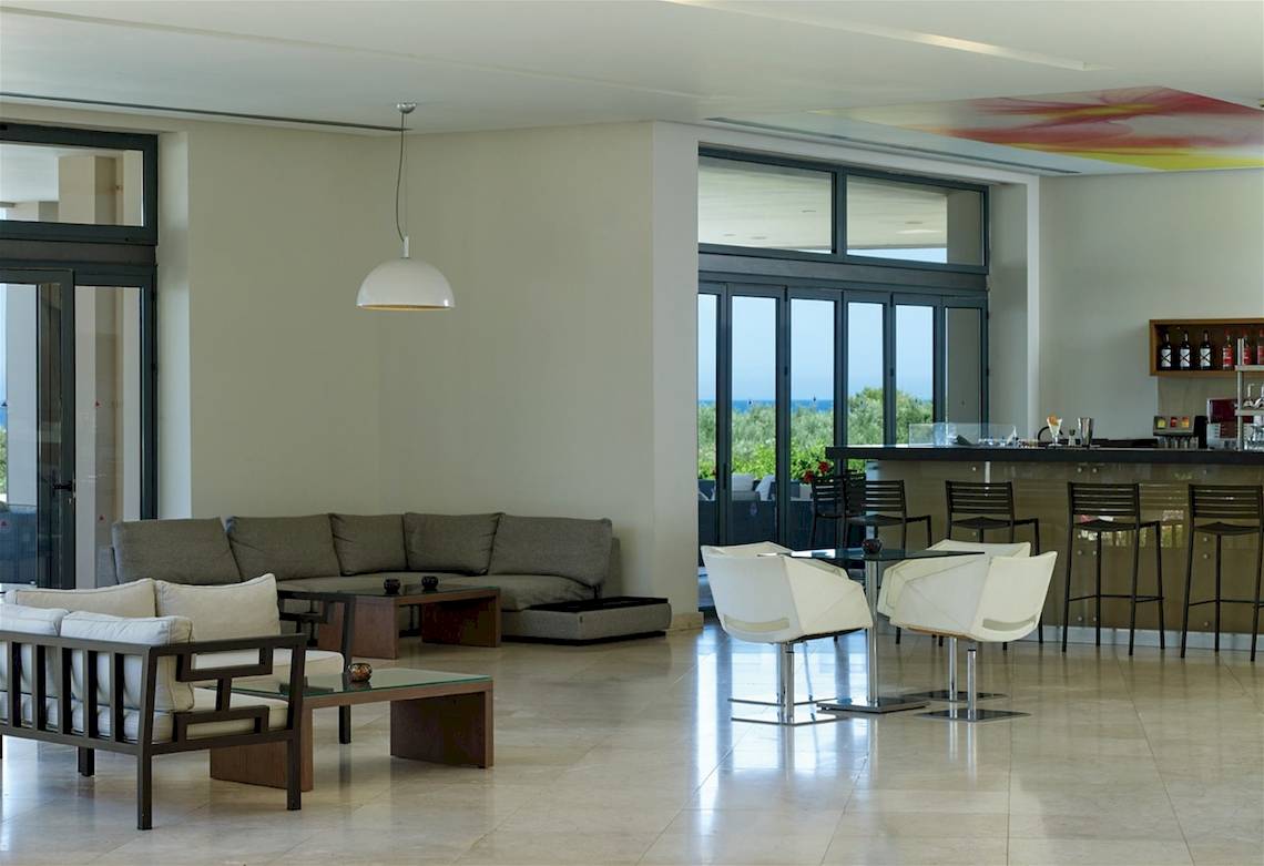 Lobby des Atlantica Eleon Grand Resort mit Couch, Tischen und Bar.