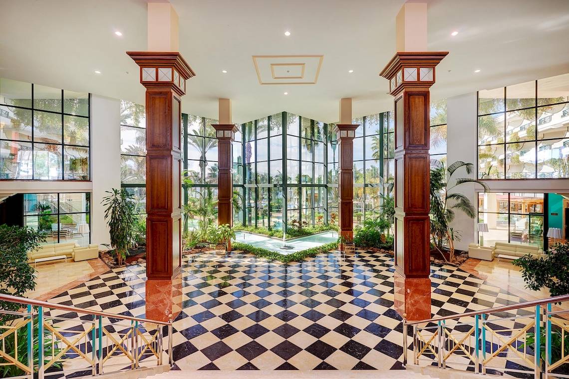 Lobby des Hipotels Natura Palace mit schwarzen und weißen Fliesen und großen Glaswänden.