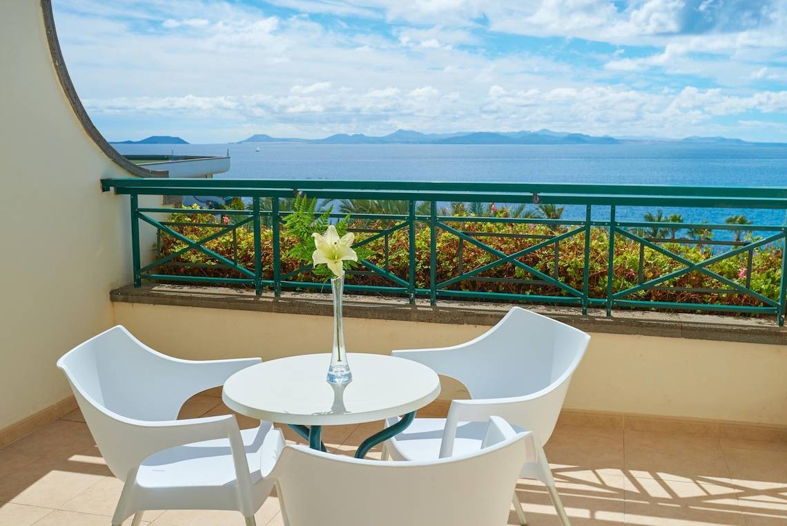 Balkon des Hipotels Natura Palace mit Blick auf das Meer und eine Wiese.
