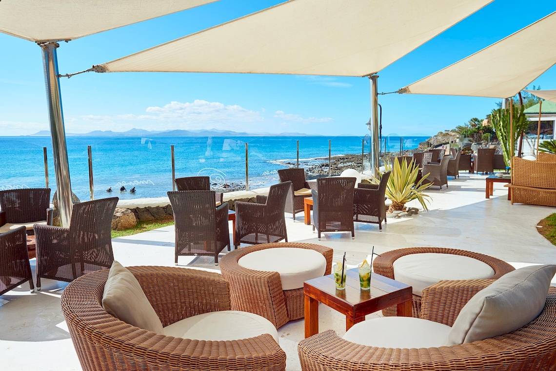 Außenbereich des Hipotels Natura Palace mit Blick auf das Meer und Sonnenschirmen.