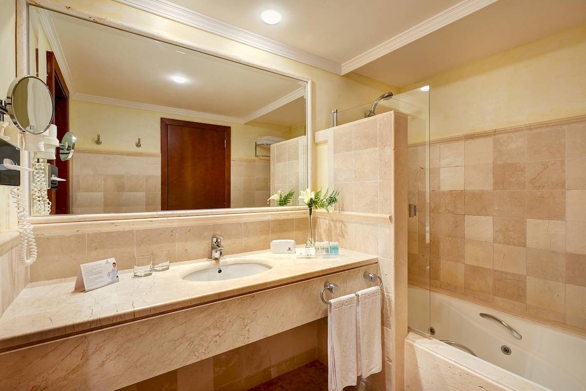 Badezimmer des Hipotels Natura Palace mit Waschbecken, Spiegel und Badewanne.