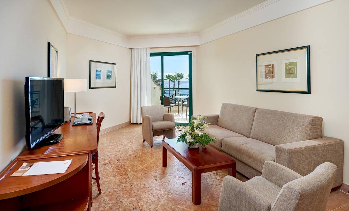 Wohnzimmer des Hipotels Natura Palace mit Sofa, Tisch, Fernseher und Meerblick