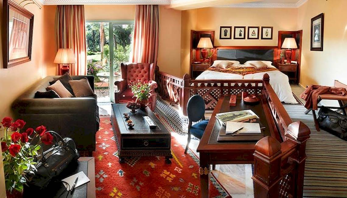 Innenansicht der Suite im Palmeraie Palace mit Bett, Wohnzimmer und Schreibtisch.