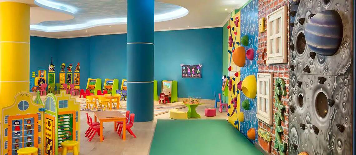 Das kinderfreundliche Spielzimmer im DoubleTree by Hilton Resort & Spa Marjan Island mit bunten Möbeln und einer Kletterwand.