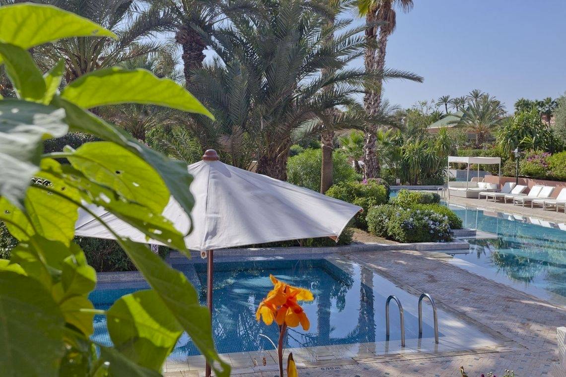 Palmeraie Palace Poolbereich mit Schirm und Sonnenliegen.