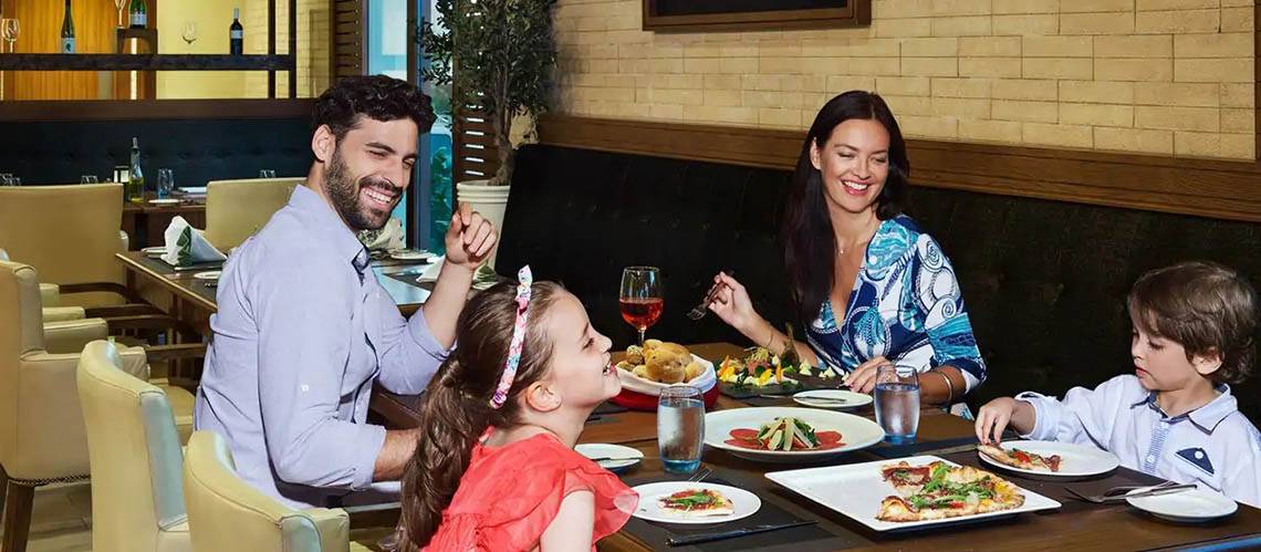 Eine Familie isst im Restaurant des DoubleTree by Hilton Resort & Spa Marjan Island.