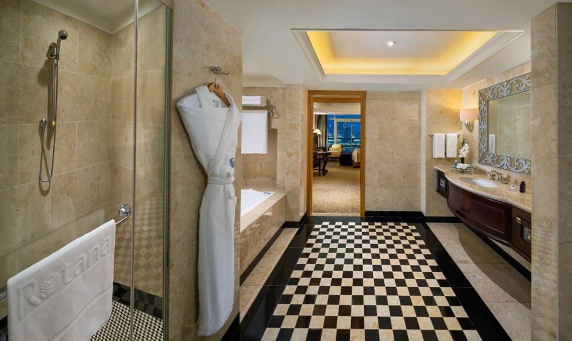 Badezimmer im Beach Rotana Hotel mit Badewanne, Dusche, Waschbecken und Marmorboden.