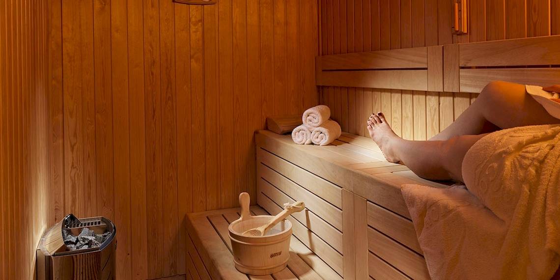 Eine Person entspannt sich in einer Holzsauna im Myconian Korali Relais & Chateaux Hotel.