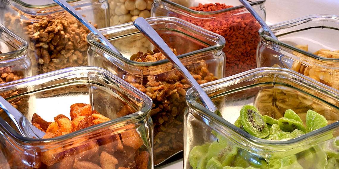 Mehrere Glasbehälter mit verschiedenen Früchten, Nüssen und Getreidesorten.