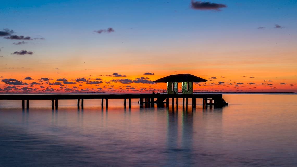 Barefoot Eco Hotel am Wasser bei Sonnenuntergang mit einer blauen und orangefarbenen Himmel.