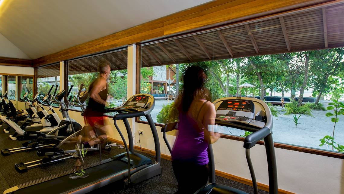 Fitnessraum im Barefoot Eco Hotel mit mehreren Läufern auf Laufbändern und großer Fensterfront.