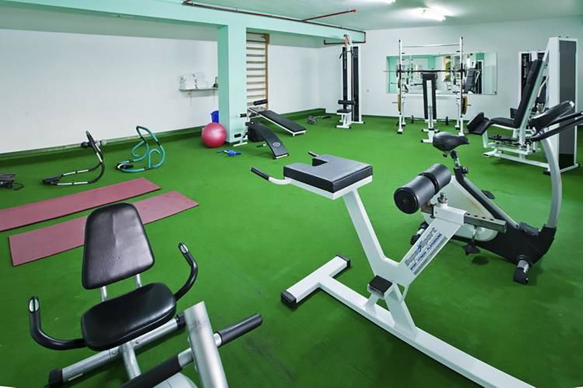 Fitness-Center im Corali Hotel mit verschiedenen Trainingsgeräten und einer grünen Trainingsfläche.