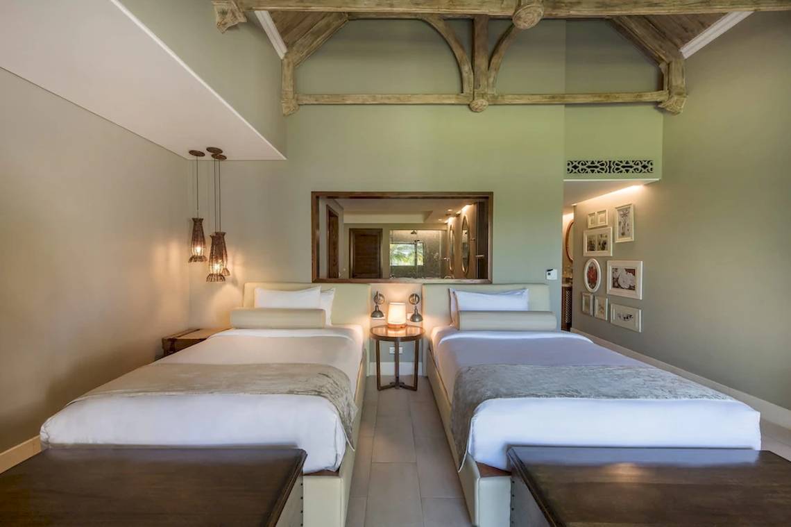 Zwei Betten im Schlafzimmer des JW Marriott Mauritius Resort mit einem Nachttisch und einem Spiegel