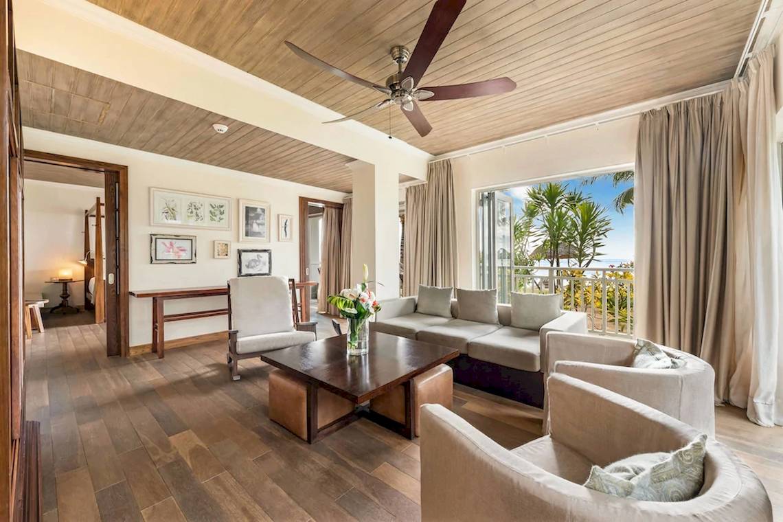 Wohnbereich im JW Marriott Mauritius Resort mit einem Sofa, einem Tisch und einem Blick auf den Ozean.