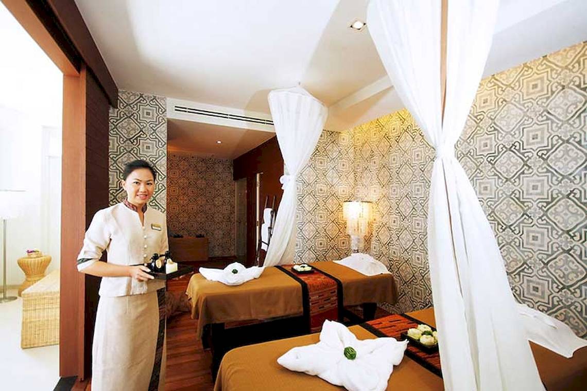 Massageraum im Cape Panwa Hotel mit einer Mitarbeiterin, die ein Tablett mit Gegenständen hält.