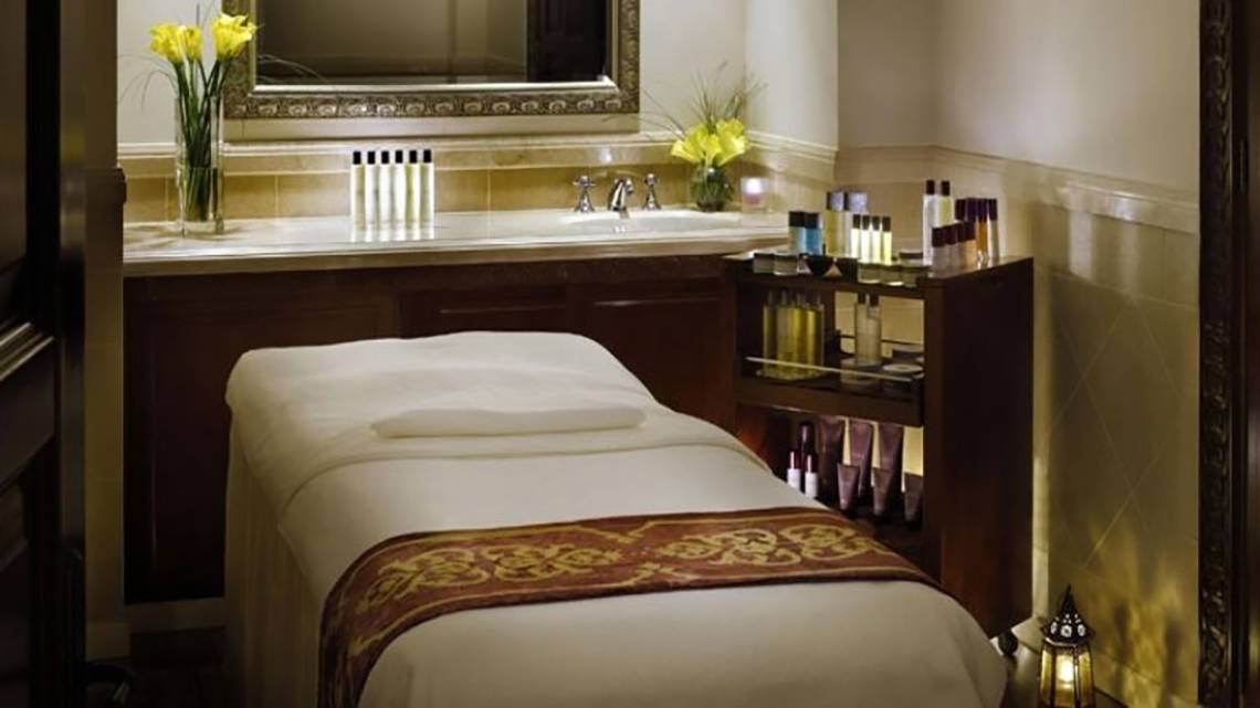Luxuriöser Spa-Behandlungsraum im Palace At One & Only Royal Mirage mit Massageliege, Waschbecken und Kosmetikprodukten.