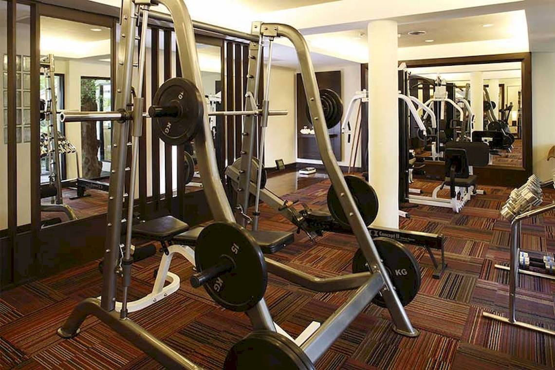 Fitnesscenter im Cape Panwa Hotel mit verschiedenen Geräten wie Hanteln und Laufbändern.