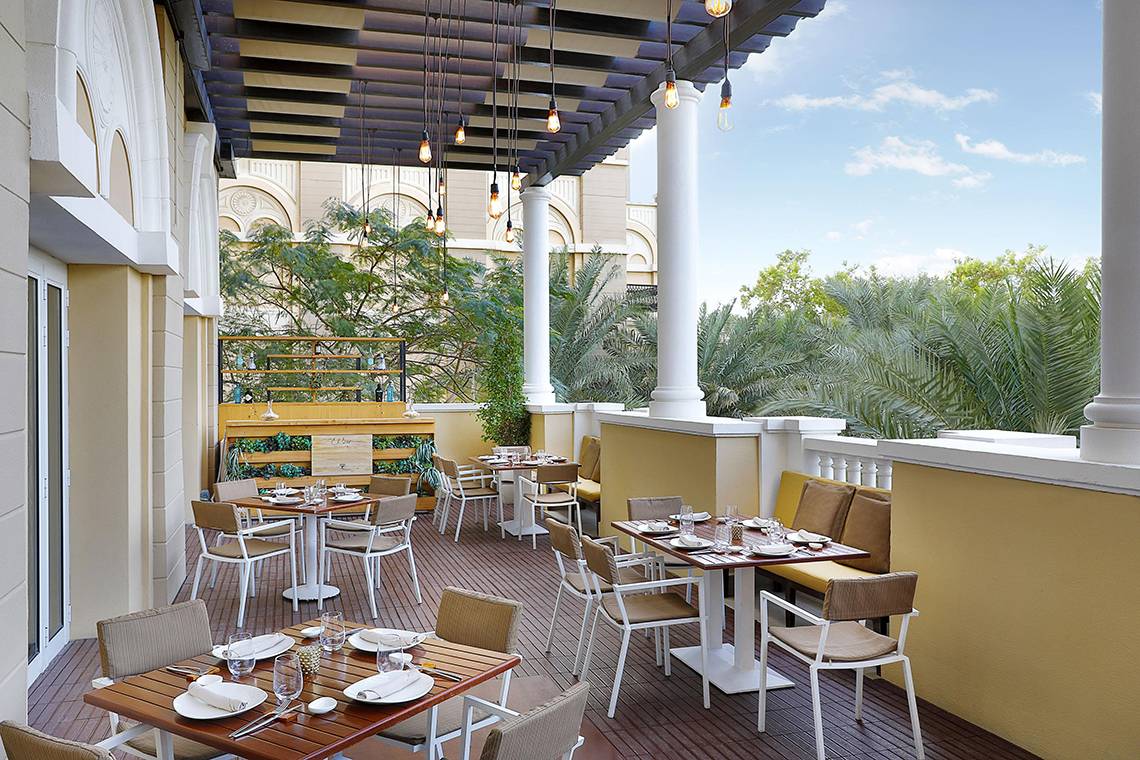 Außenterrasse des Westin Dubai Mina Seyahi Beach Resort & Marina mit Tischen und Stühlen.