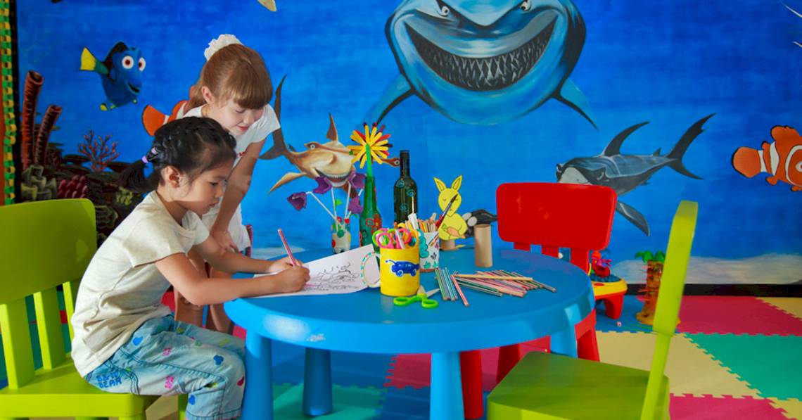 Kinderzimmer im Angsana Velavaru Hotel mit einer Wandmalerei von Haien und Fischen.